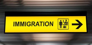 Yellow immigration sign with arrow pointing right.