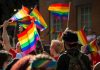 People holding rainbow flags at an outdoor gathering