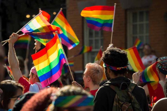 People holding rainbow flags at an outdoor gathering