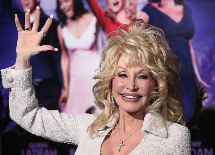 Dolly Parton smiling and waving in front of a crowd of people