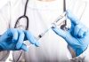 Doctor filling syringe with vaccine from vial.