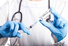 Doctor filling syringe with vaccine from vial.