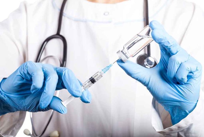 Doctor filling syringe with vaccine from vial.