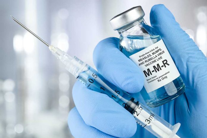 Syringe and MMR vaccine vial in gloved hand