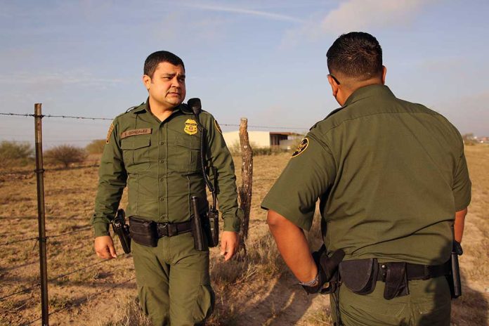 Two uniformed officers standing outdoors near a fence.