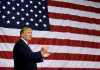 Man clapping in front of large American flag