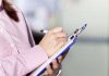 Person writing on a clipboard with a pen
