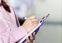 Person writing on a clipboard with a pen