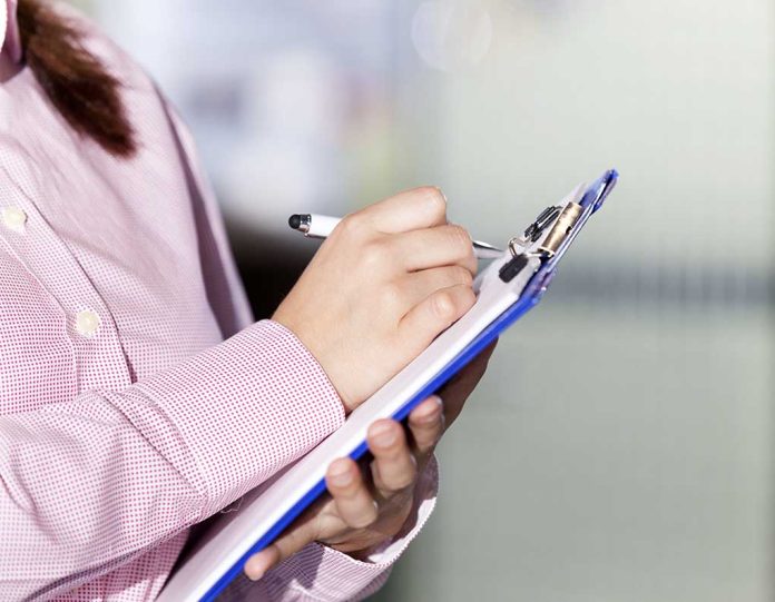 Person writing on a clipboard with a pen