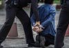 Police arresting person kneeling on pavement