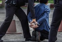 Police arresting person kneeling on pavement