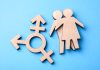 Wooden figures and transgender symbol on blue background