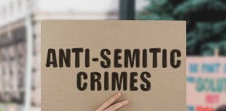 hand holding up a sign reading anti-semitic crimes