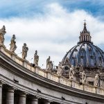 St Peters Basilica dome with statues under blue sky