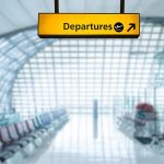 yellow Departures sign hangs in an airport terminal