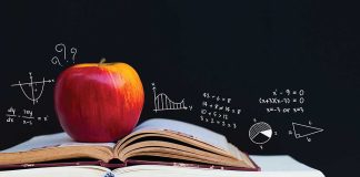 Apple on books with math equations on blackboard