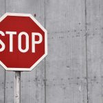 Red stop sign against concrete wall background