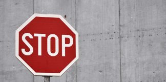 Red stop sign against concrete wall background