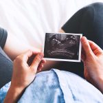 pregnant woman holding a picture of sonagram showing a child