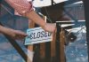 Hand placing closed sign on glass door