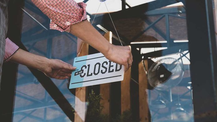 1162554778 featured image Hand placing closed sign on glass door