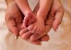 Adult hands holding a babys tiny feet