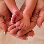 Adult hands holding a babys tiny feet