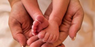 Adult hands holding a babys tiny feet