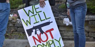 Protest sign reads We Will Not Comply
