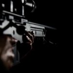 Person holding a rifle in dim lighting