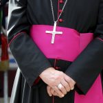 Person wearing clerical robes with cross necklace