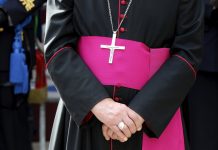 Person wearing clerical robes with cross necklace