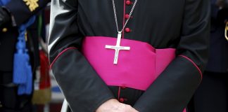 Person wearing clerical robes with cross necklace