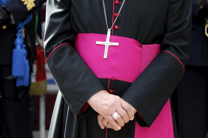 2222602787 featured image Person wearing clerical robes with cross necklace