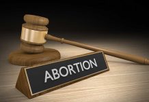 Gavel and sign reading Abortion on a wooden surface