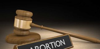 Gavel and sign reading Abortion on a wooden surface