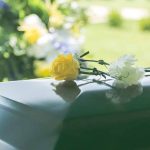 Two flowers on a casket at a funeral