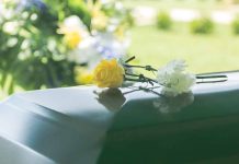 Two flowers on a casket at a funeral