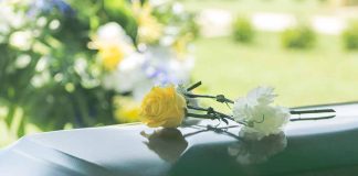 Two flowers on a casket at a funeral