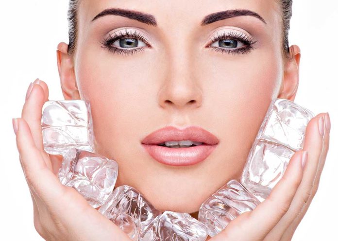 Woman holding ice cubes near her face