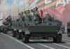Tanks with military personnel in street parade formation