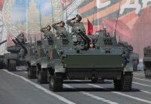 Tanks with military personnel in street parade formation