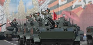 Tanks with military personnel in street parade formation