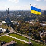 Large Ukraine flag with cityscape in background