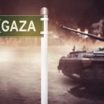 Sign pointing to Gaza with tank nearby