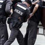 Police officers arresting a handcuffed person