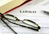 Lawsuit paperwork with glasses pen and an open book