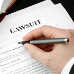 Hand holding pen filling out lawsuit form
