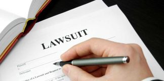 Hand holding pen filling out lawsuit form