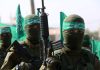 Armed masked men with green flags in military fatigues.